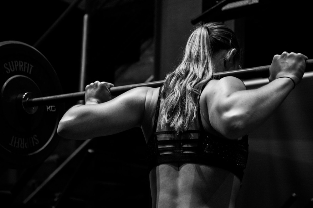 Athlete holding a barbell across her back before a squat