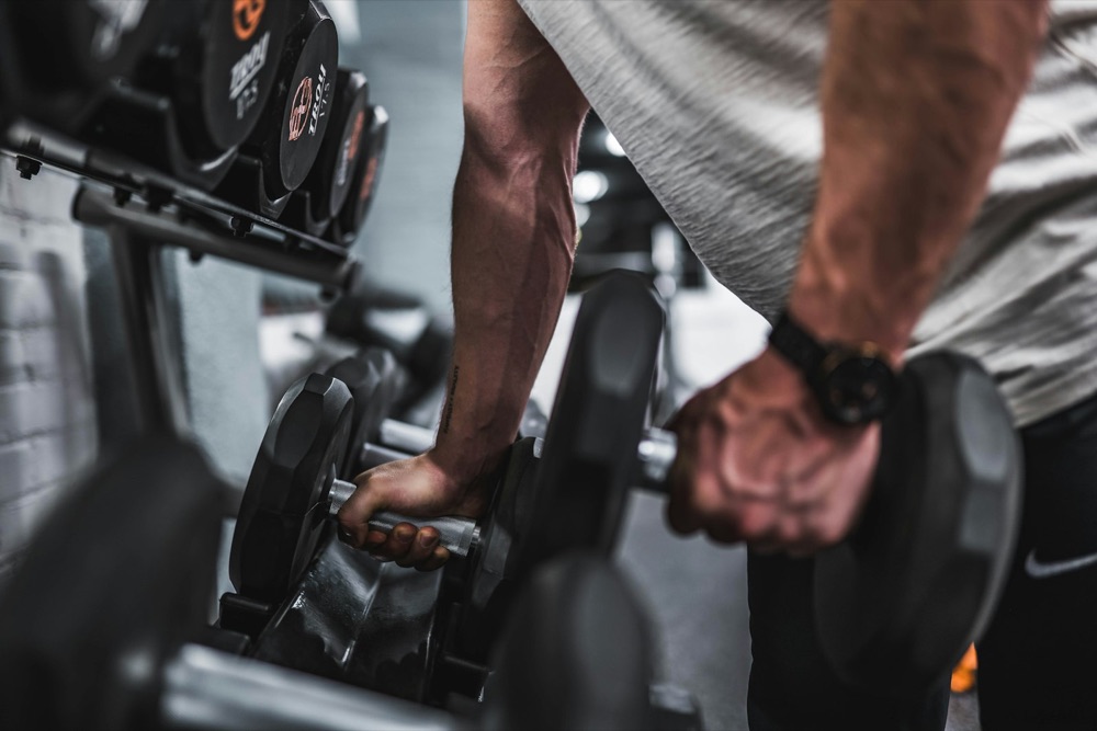 Hand gripping a dumbbell on a rack