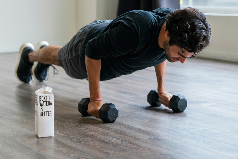 Man doing push-ups beside a water carton